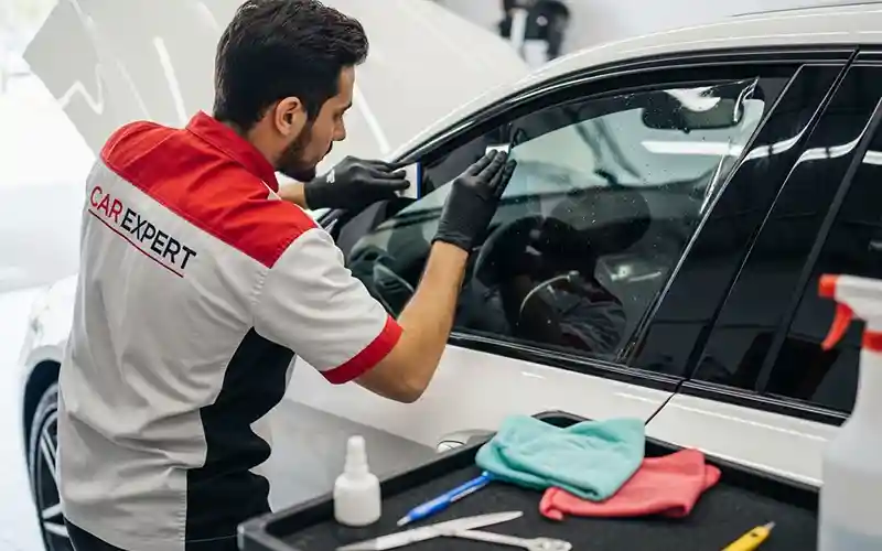 Auto detailing technician performing full car tinting service on a vehicle in Dubai