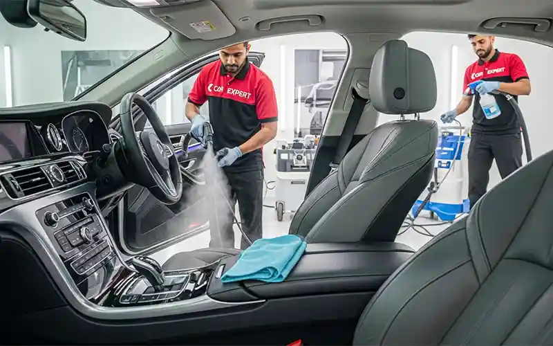 Auto spa technician performing interior deep cleaning and sanitization on a car in Dubai