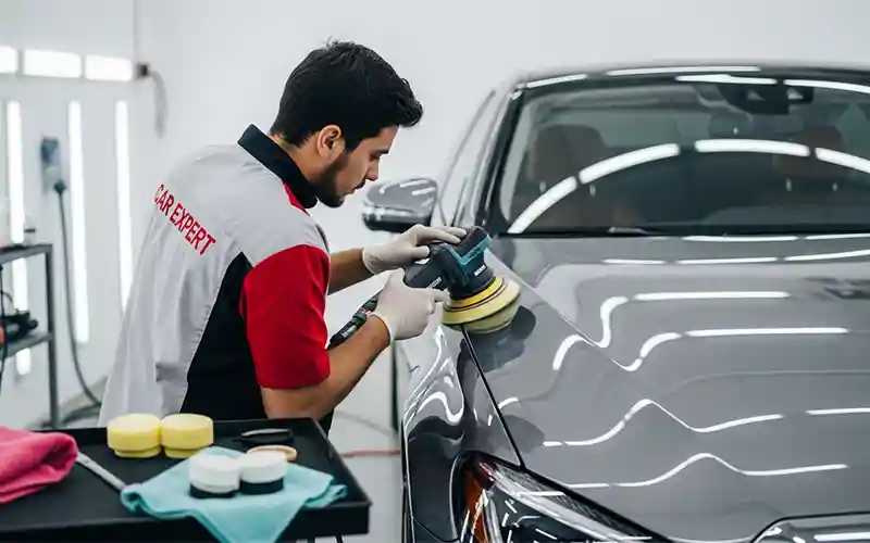 Auto spa technician performing paint correction and polishing on a car in Dubai